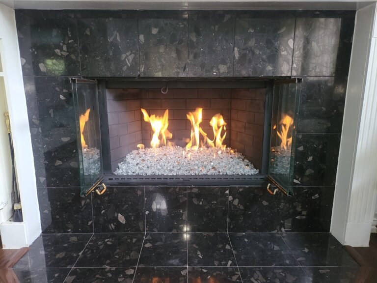Projects gas fireplace with white fire glass and custom glass doors in Frisco Texas