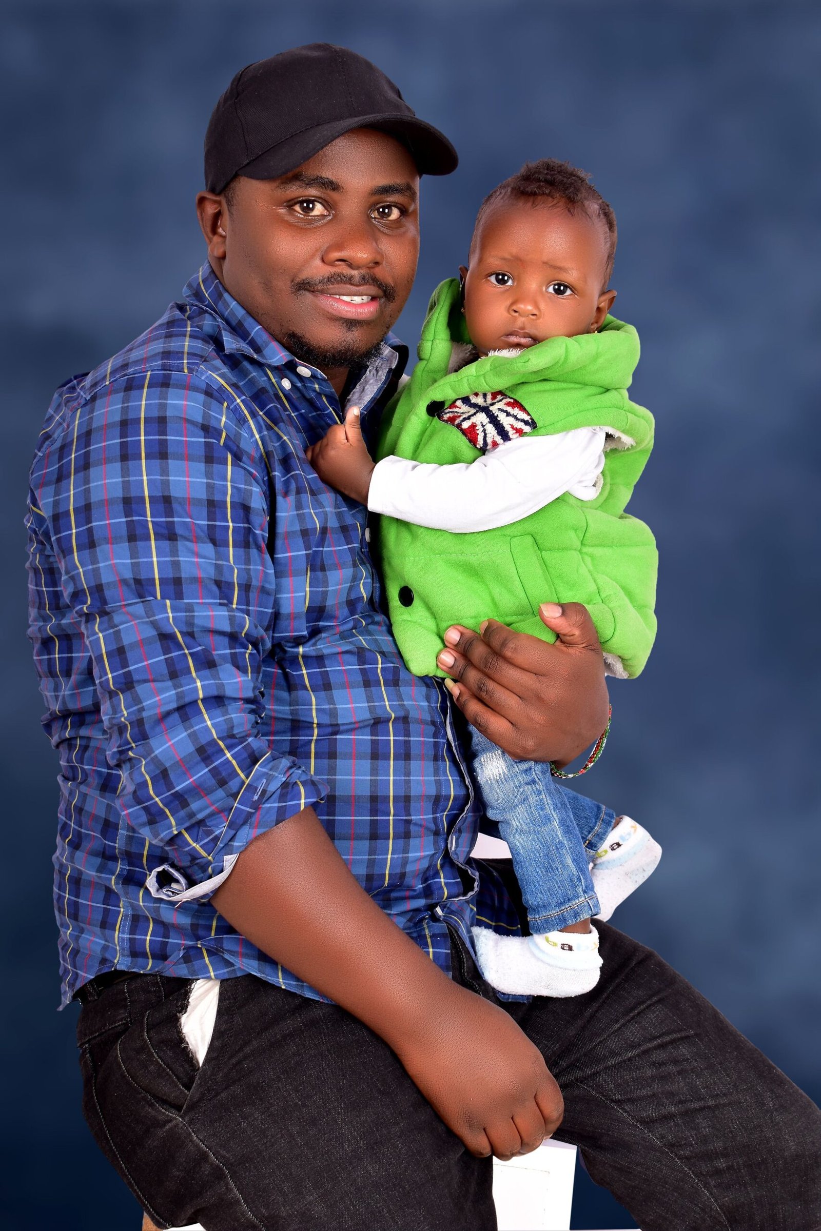 Father holding baby in a colorful studio portrait, showcasing family bond.