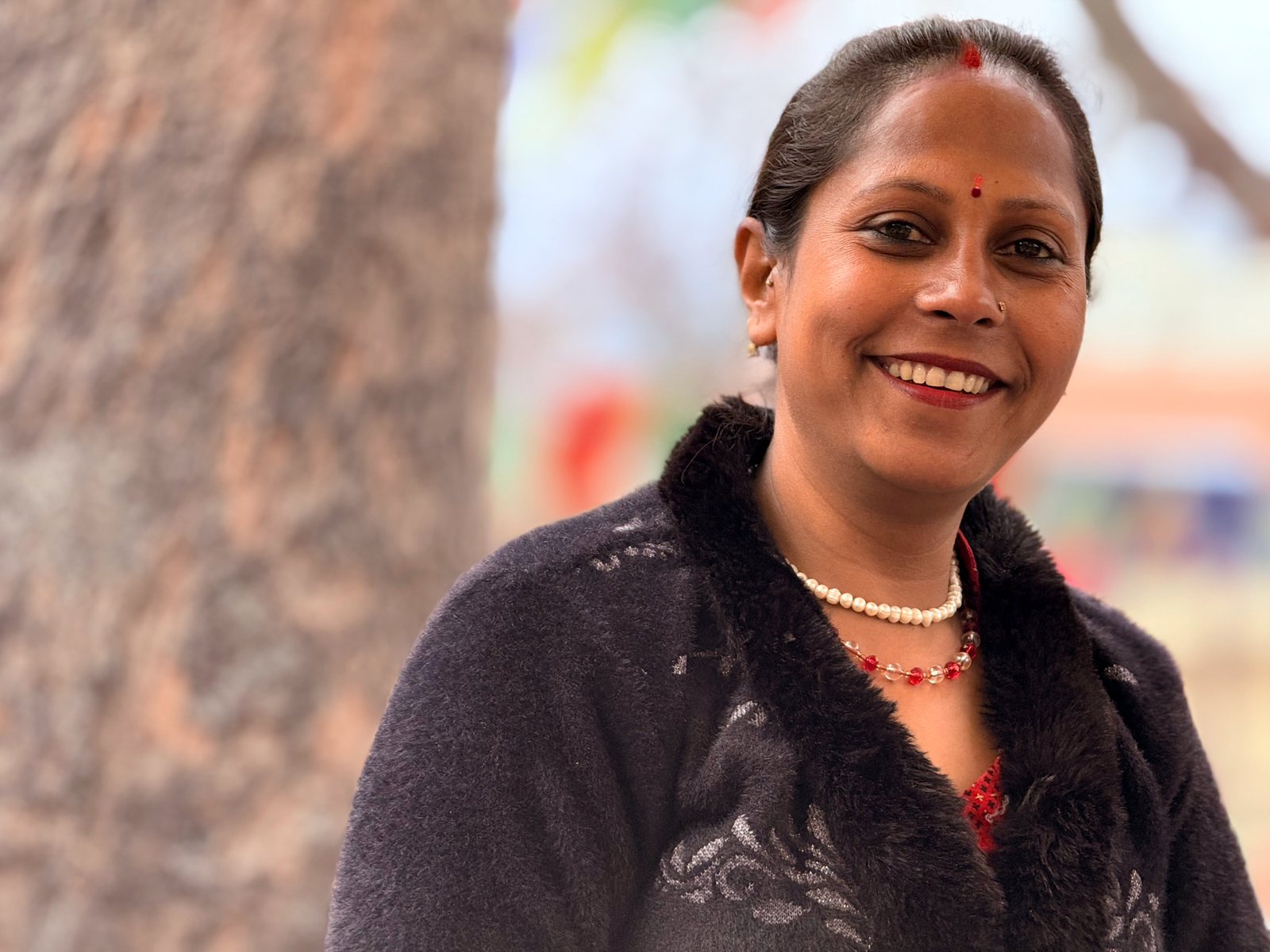 Portrait of a smiling woman outdoors in Kathmandu, capturing authentic Nepalese culture.